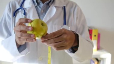 Elma tutan ve mezura kullanan genç bir doktor. 