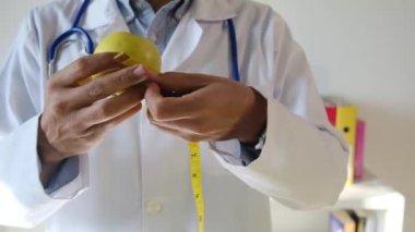 Elma tutan ve mezura kullanan genç bir doktor. 