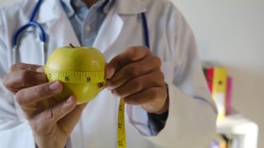 Elma tutan ve mezura kullanan genç bir doktor. 