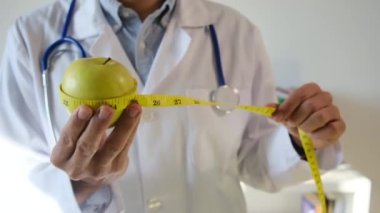 Elma tutan ve mezura kullanan genç bir doktor. 