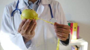 Elma tutan ve mezura kullanan genç bir doktor. 