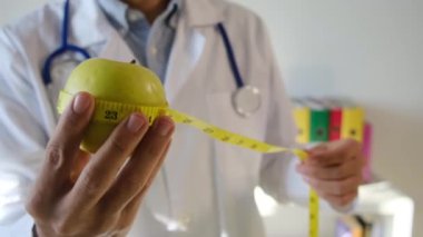 Elma tutan ve mezura kullanan genç bir doktor. 