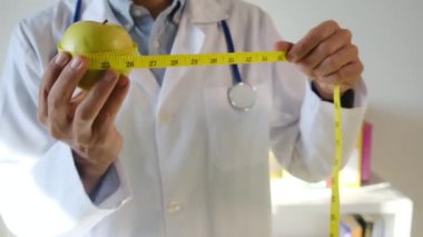 Elma tutan ve mezura kullanan genç bir doktor. 