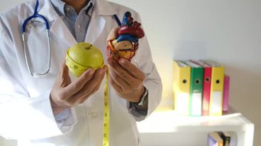Doktor kalp modeli, elma ve mezurayı hastane, sağlık ve sağlık hizmetleri konseptinde tutuyor.