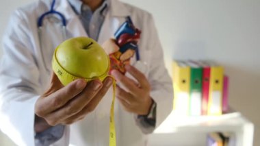 Doktor kalp modeli, elma ve mezurayı hastane, sağlık ve sağlık hizmetleri konseptinde tutuyor.