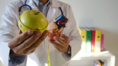 Doktor kalp modeli, elma ve mezurayı hastane, sağlık ve sağlık hizmetleri konseptinde tutuyor.
