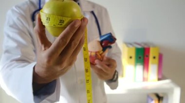 Doktor kalp modeli, elma ve mezurayı hastane, sağlık ve sağlık hizmetleri konseptinde tutuyor.