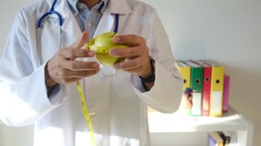 Elma tutan ve mezura kullanan genç bir doktor. 