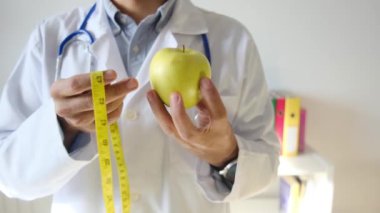 Elma tutan ve mezura kullanan genç bir doktor. 