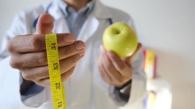 Elma tutan ve mezura kullanan genç bir doktor. 