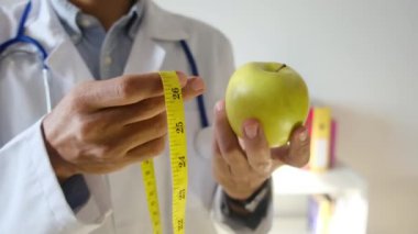 Elma tutan ve mezura kullanan genç bir doktor. 