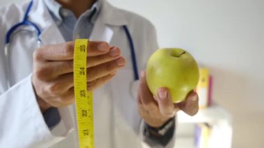 Elma tutan ve mezura kullanan genç bir doktor. 