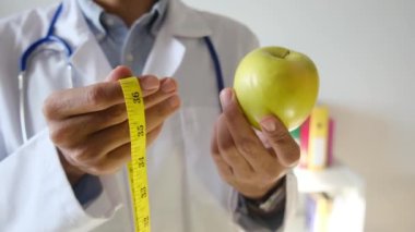 Elma tutan ve mezura kullanan genç bir doktor. 