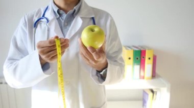 Elma tutan ve mezura kullanan genç bir doktor. 