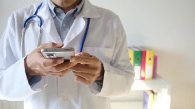 Doktor klinikte akıllı telefon tutuyor.