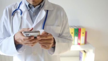 Doktor klinikte akıllı telefon tutuyor.