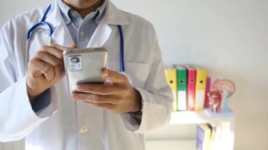 Doktor klinikte akıllı telefon tutuyor.