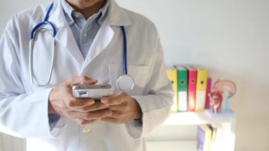 Doktor klinikte akıllı telefon tutuyor.
