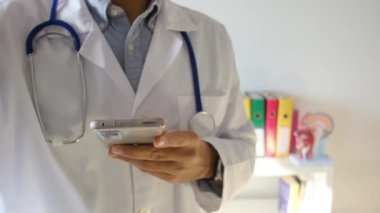 Doktor klinikte akıllı telefon tutuyor.