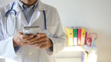 Doktor klinikte akıllı telefon tutuyor.