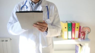 Klinikte elinde tablet bilgisayar tutan bir doktor.