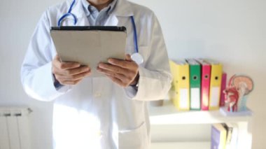 Klinikte elinde tablet bilgisayar tutan bir doktor.