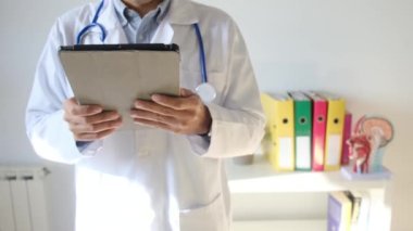 Klinikte elinde tablet bilgisayar tutan bir doktor.