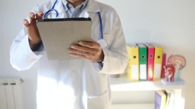 Klinikte elinde tablet bilgisayar tutan bir doktor.