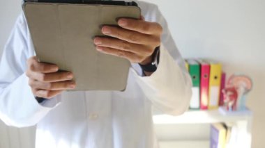 Klinikte elinde tablet bilgisayar tutan bir doktor.