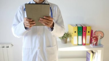 Klinikte elinde tablet bilgisayar tutan bir doktor.