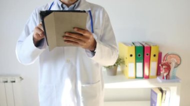 Klinikte elinde tablet bilgisayar tutan bir doktor.