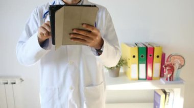 Klinikte elinde tablet bilgisayar tutan bir doktor.