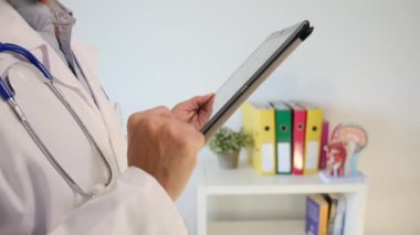 Klinikte elinde tablet bilgisayar tutan bir doktor.