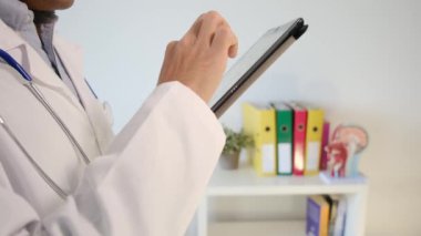 Klinikte elinde tablet bilgisayar tutan bir doktor.
