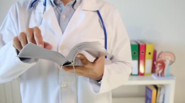 Genç doktor hastanede kitap tutuyor.