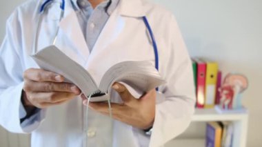 Genç doktor hastanede kitap tutuyor.