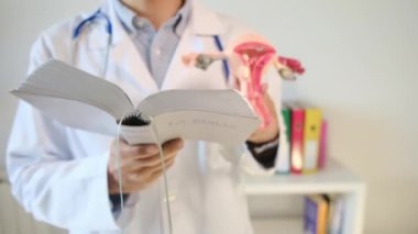 Doktor rahim modelini ve kitabını klinikte tutuyor.