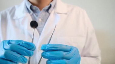 Erkek doktor dişçilik aletleri tutuyor. 