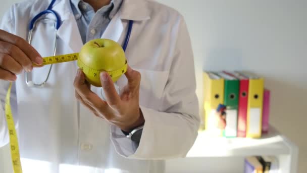 Νεαρός Γιατρός Κρατώντας Μήλο Και Ταινία Μέτρησης — Αρχείο Βίντεο