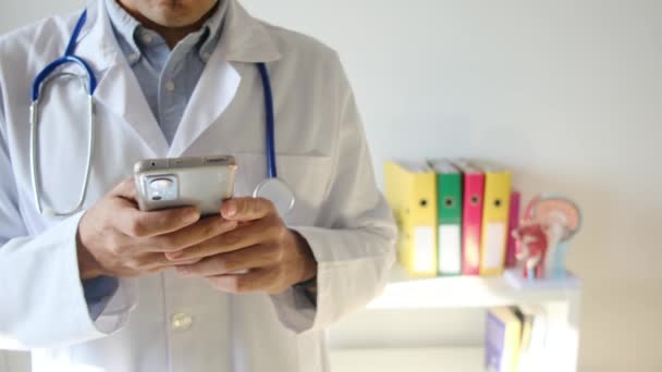 Doctor Sosteniendo Teléfono Inteligente Clínica — Vídeo de stock
