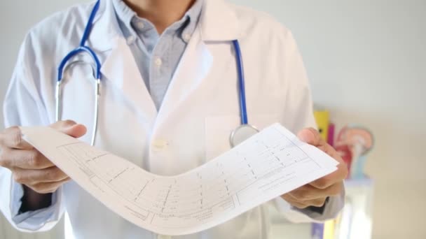 Γιατρός Κρατώντας Καρδιογράφημα Χαρτί Μπροστά Από Τον Ασθενή Του — Αρχείο Βίντεο
