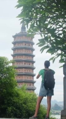 Sırt çantalı bir kadın gezgin tapınağın fotoğrafını çekiyor, seyahat ediyor.