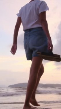 Sahilde çıplak ayakla yürüyen bir kadın. 