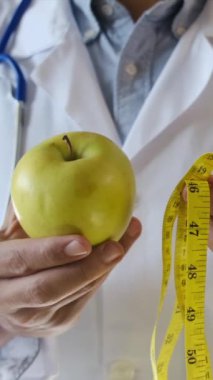 Elma tutan ve mezura kullanan genç bir doktor. 