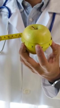 Elma tutan ve mezura kullanan genç bir doktor. 