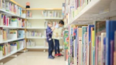 Küçük çocuklar kütüphanede kitap seçiyor.