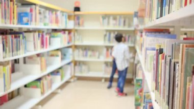 Küçük çocuklar kütüphanede kitap seçiyor.