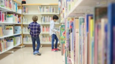 Küçük çocuklar kütüphanede kitap seçiyor.