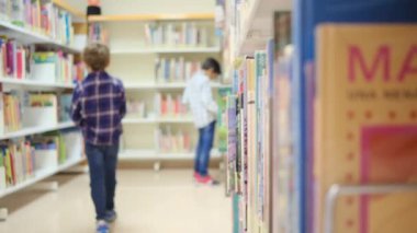 Küçük çocuklar kütüphanede kitap seçiyor.