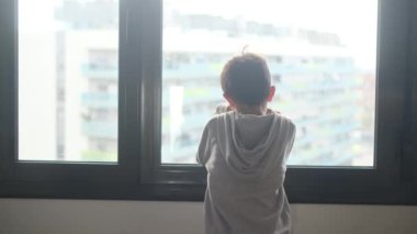 Kapüşonlu bir çocuğun pencereden dışarı bakışı..